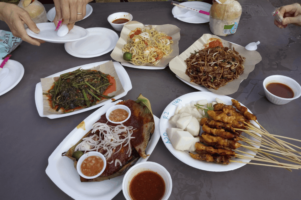 A vibrant spread of Southeast Asian hawker food featuring satay skewers, noodles, grilled fish, papaya salad, stir-fried vegetables, and dipping sauces—showcasing the delicious food and local dishes found in singapore's hawker centres like Maxwell Food Centre, Lau Pa Sat, Tiong Bahru Market, Satay Street, Airport Road Food Centre, and Little India. This hawker centre scene reflects the heart of singapore's identity and hawker culture, with food stalls and hawker stalls offering char kway teow, hainanese chicken rice, nasi lemak, hokkien mee, chilli crab, and indian food. Located in the central business district near Marina Bay, City Hall, Orchard Road, and Tanjong Pagar, hawker centers are a central location for expat life, lunch rush, and making new friends. A short walk from international schools, mass rapid transit, and the subway system, these open air food courts are a must visit spot for expats moving abroad. With most stalls recently renovated and other stalls offering hidden gems praised by Anthony Bourdain, hawker centers have a significant impact on expat packages, school fees, health insurance, employment pass, property cost, and services. This hawker center guide offers advice, tips, and insights into the living culture, food, business, living, and life in Singapore and Southeast Asia—a world-class destination to eat without too much cost and a living food culture, connect with your home country, and explore the rewards of expat living.