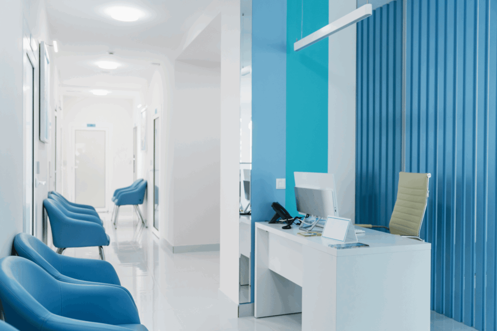 Modern clinic reception area with blue waiting chairs, white tile floors, and a sleek desk setup—reflecting Singapore’s commitment to professional, welcoming healthcare spaces for patients and newcomers alike.