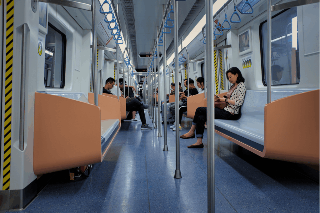 Interior of a clean, modern Singapore MRT train during peak hours, with passengers seated and standing near priority seats, showcasing the mass rapid transit system used by expats and locals alike. This Singapore MRT Guide for Expats highlights MRT rides across MRT lines including the North South Line, East West Line, Circle Line, Downtown Line, North East Line, Thomson East Coast Line, and LRT lines like Bukit Panjang LRT. Riders can explore Singapore with cost-effective public transport options such as bus rides, public buses, and train services, using contactless bank cards, mobile wallets like Apple Pay, Samsung Pay, Fitbit Pay, or physical cards like EZ-Link, NETS FlashPay, and travel cards from other countries. Key MRT stations and train stations such as Dhoby Ghaut, City Hall, Chinatown MRT, Marina Bay, Orchard Road, Raffles Place, Botanic Gardens, and Tanjong Pagar are accessible during rush hours, off peak hours, off peak times, and midnight daily. The MRT map supports journey planning with Google Maps, SimplyGo app, MyTransport app, and the official app, offering details on train frequency, operating hours, ticketing machines, admin fee info, first bus timings, and total distance. Expats can pay directly and simply tap at convenience stores or MRT stations, using single trip tickets or the Singapore Tourist Pass for every ride on Singapore’s MRT and bus service network—whether traveling one line or transferring at interchange stations.