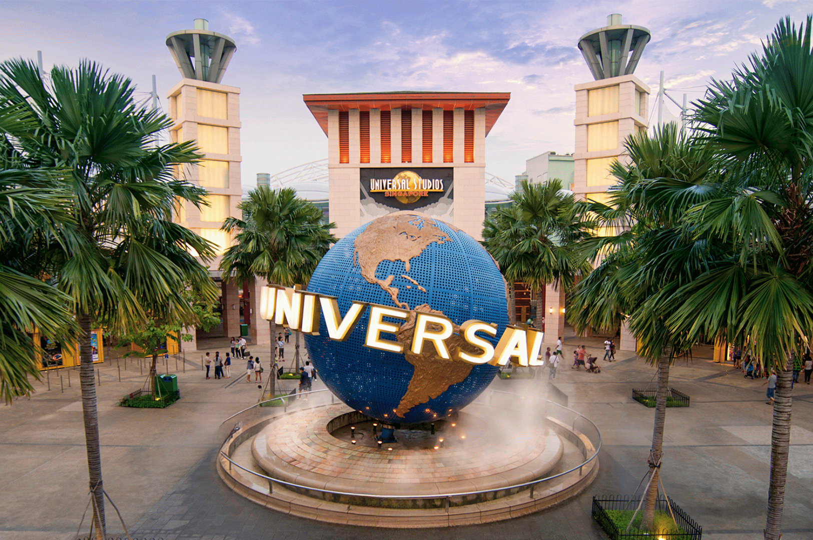 Visitors gather at the entrance of Universal Studios Singapore on Sentosa Island, where the iconic rotating globe fountain and palm-lined plaza welcome families into the theme park. The lively atmosphere and bold architecture highlight one of Singapore’s most popular kid-friendly attractions for entertainment and adventure.