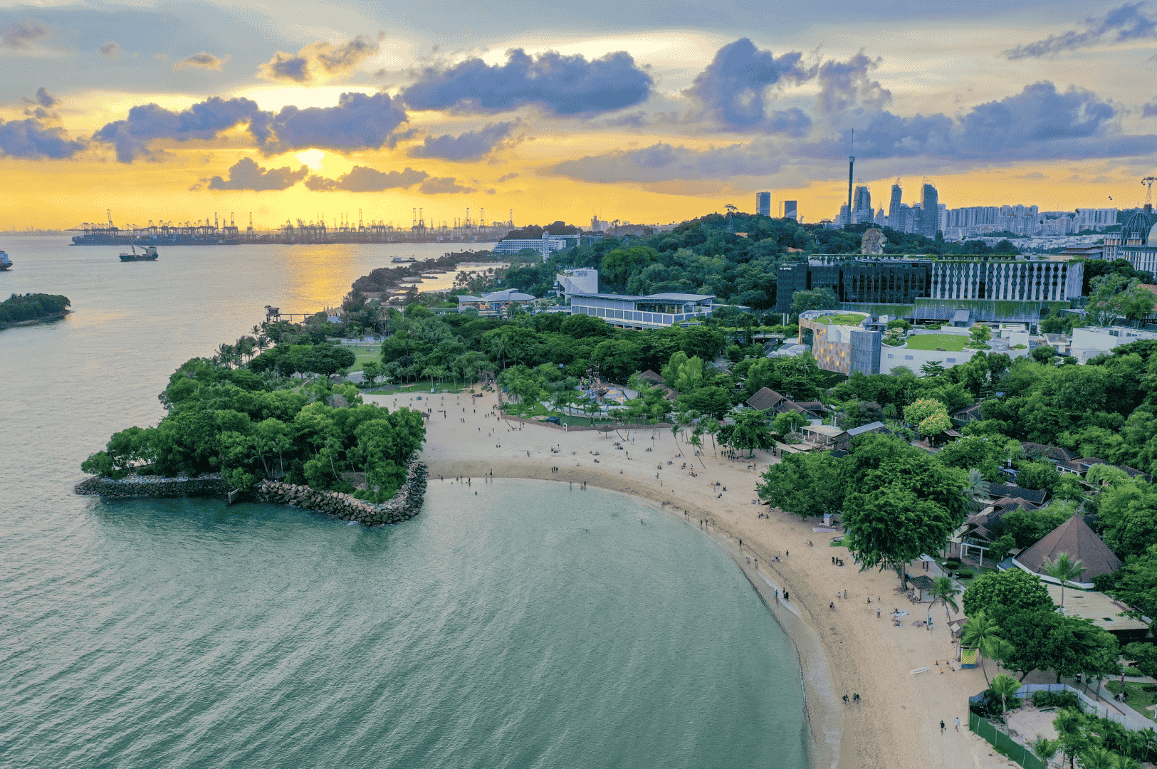 Golden sunset over a Singapore coastline where families stroll along the sandy beach, framed by lush greenery and calm waters. The scene blends natural beauty with glimpses of modern buildings and a distant port, capturing the balance of recreation, city life, and coastal charm that makes Singapore a unique family destination.