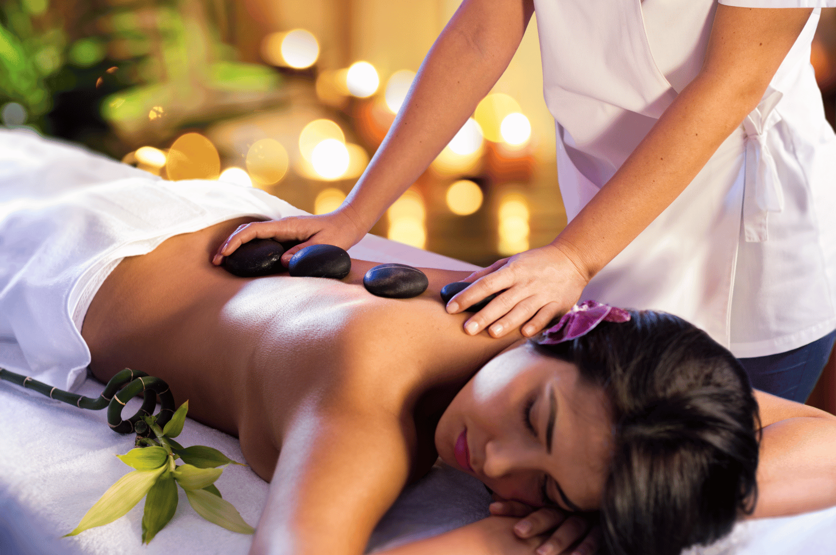 Woman receiving a hot stone massage at a serene spa—calming, wellness-focused setting ideal for a Singapore staycation feature.
