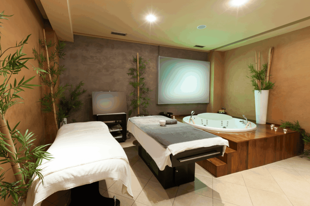 Serene spa room with a round jacuzzi tub, warm wood accents, soft lighting, and lush indoor plants—ideal for a relaxing wellness staycation in Singapore