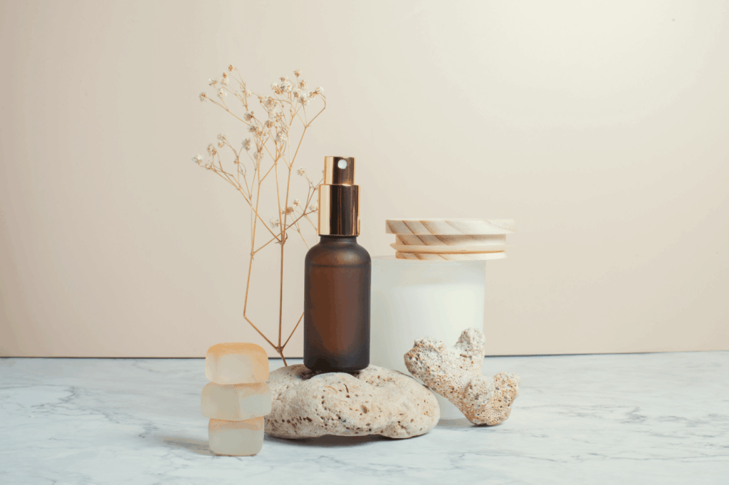 Amber glass essential oil bottle with dropper on a smooth stone, soft towels and greenery on a marble counter—calm spa vibe for a Singapore wellness staycation feature.