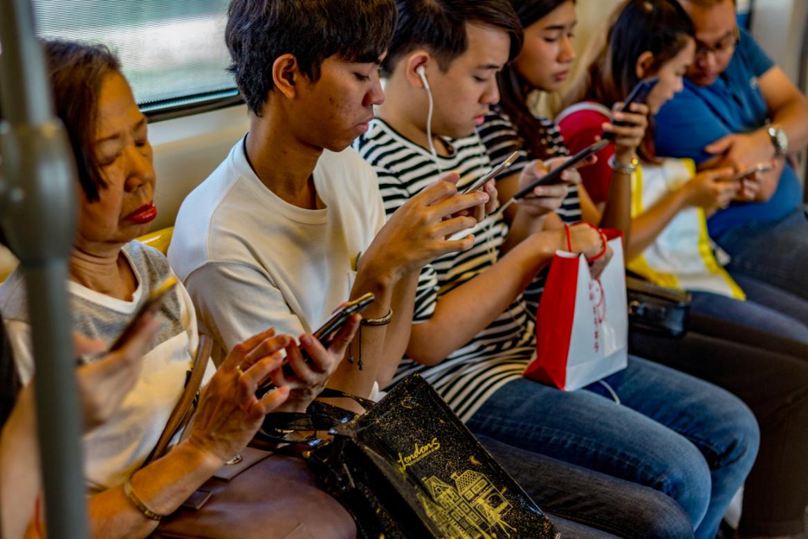 A photo of people using their phones as they travel in a public railroad transit.