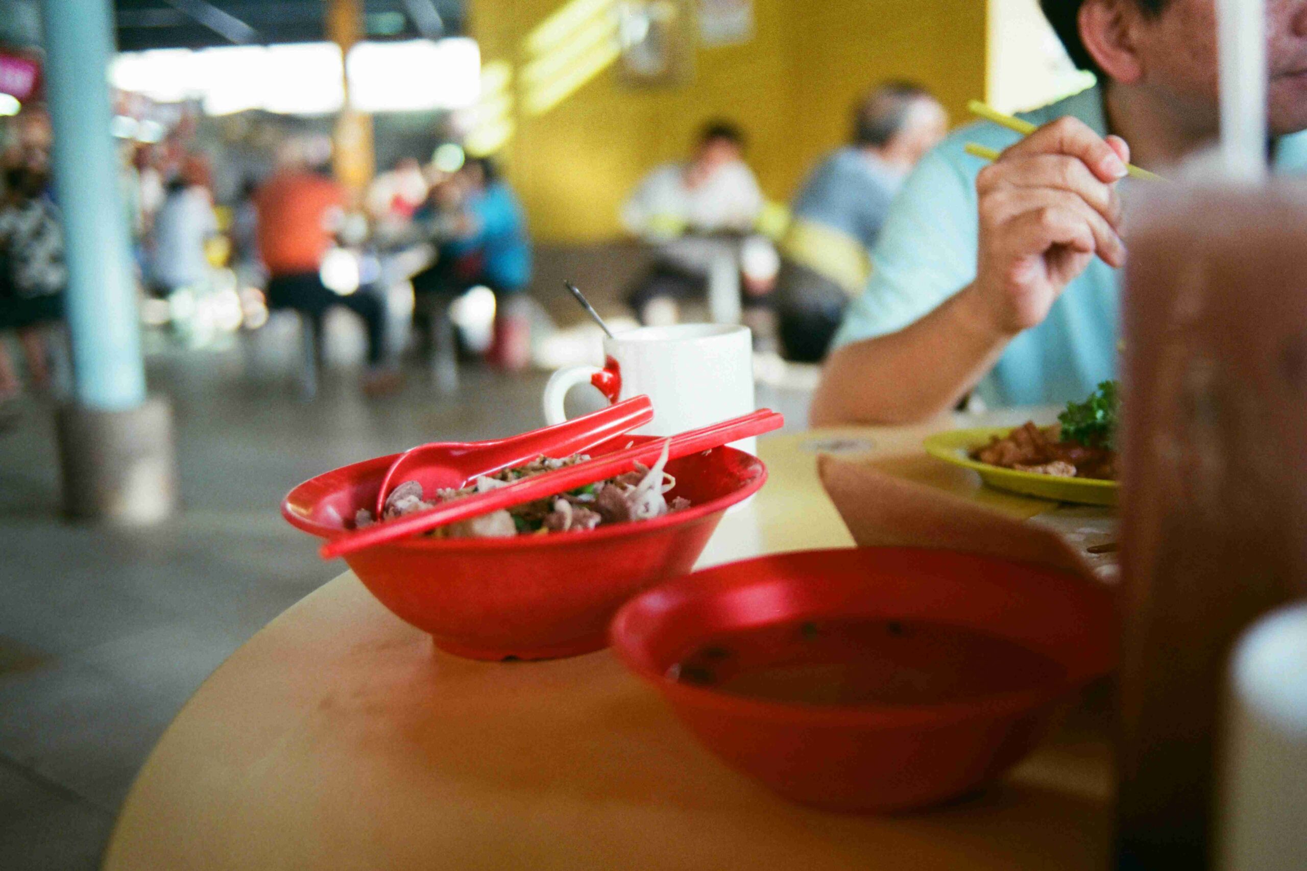A photo of an individual dining at maxwell food center with a red bowl to his side.