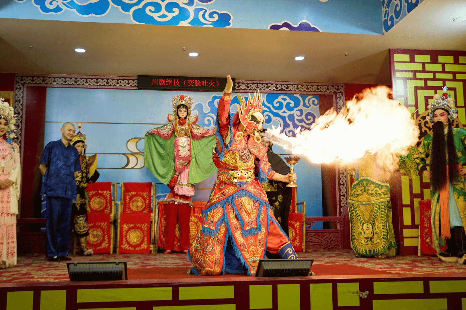 Chinese Opera performance in Singapore featuring a fire-breathing actor in ornate costume and headdress, surrounded by fellow performers against a red and gold traditional backdrop, highlighting the city’s vibrant cultural heritage.