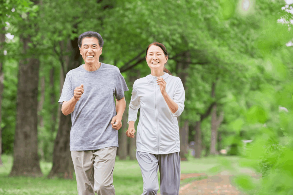 Two adults jogging along a tree-lined path in a Singapore park, illustrating active lifestyles and outdoor fitness for all ages in the city’s green spaces.