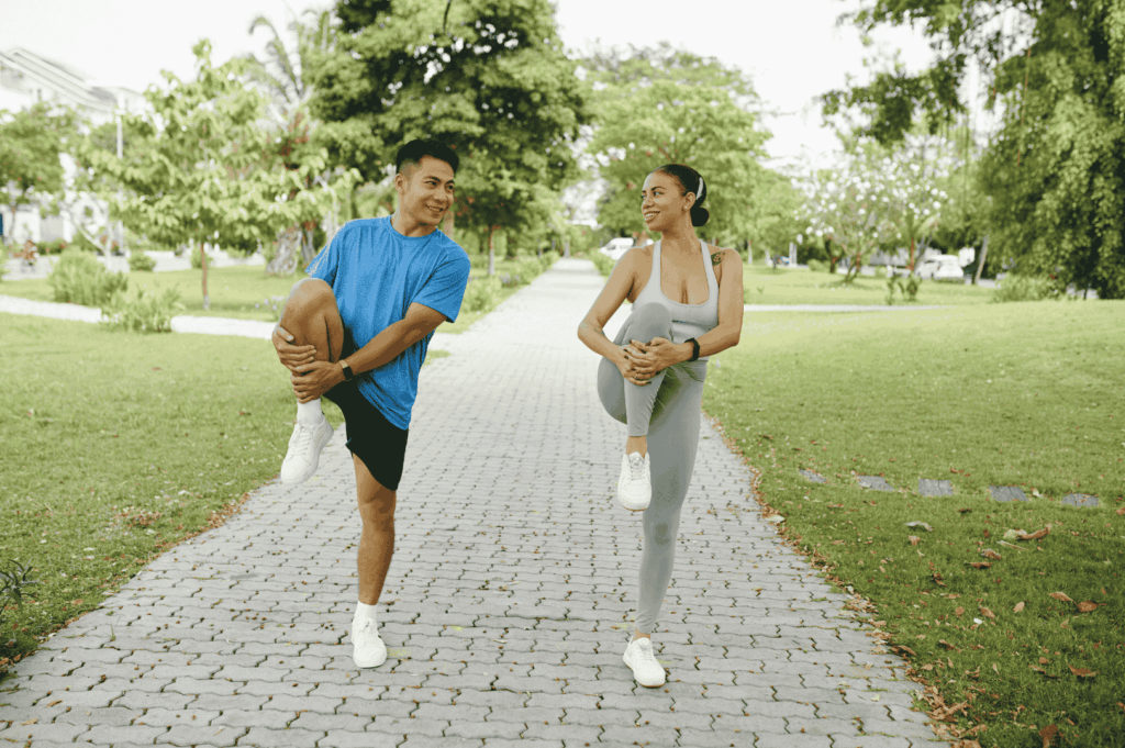 Two individuals stretching on a paved path in a Singapore park, emphasizing accessible outdoor fitness and wellness in the city’s green urban spaces.
