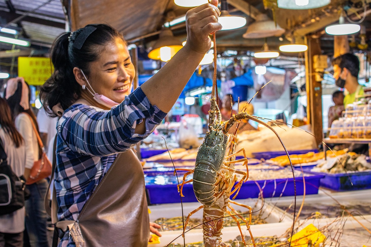 A wet market vendor holding a fresh lobster straight from the dock.