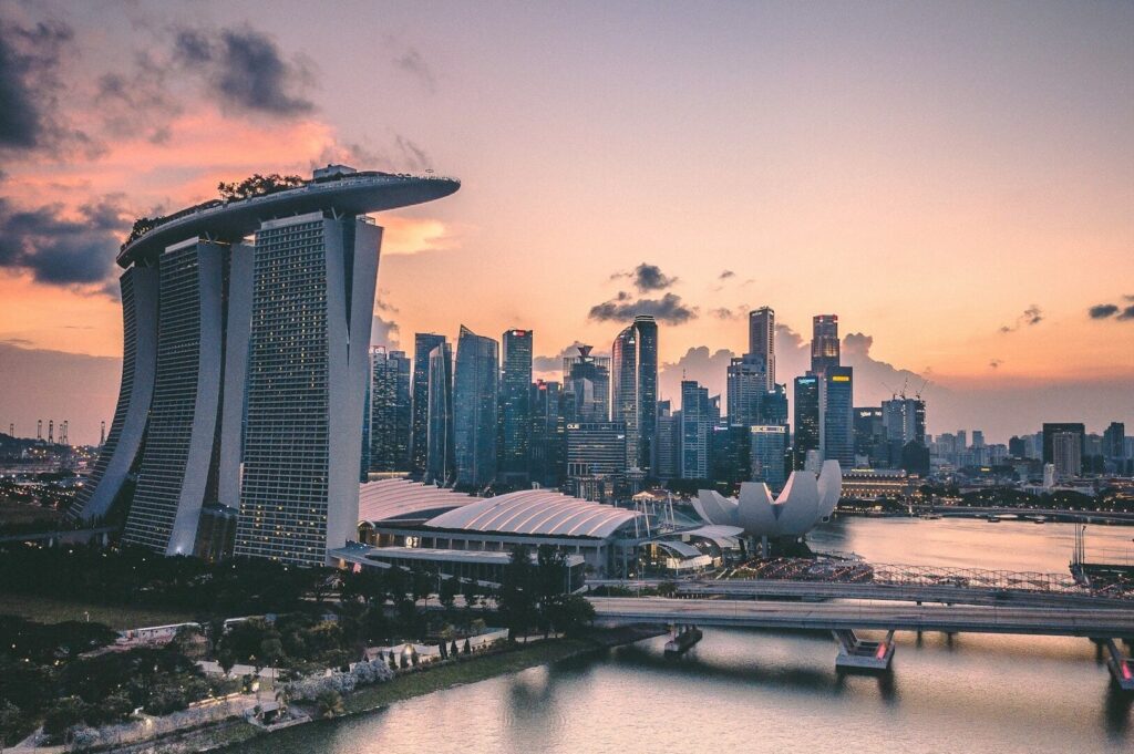 A stunning sunset casts warm hues over Singapore's skyline, highlighting its iconic architecture and urban landscape.