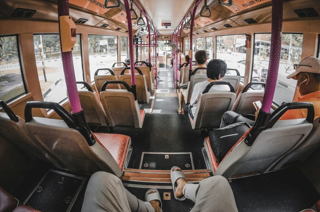 People seated on a Singapore bus, engaged in conversation and looking out the windows.