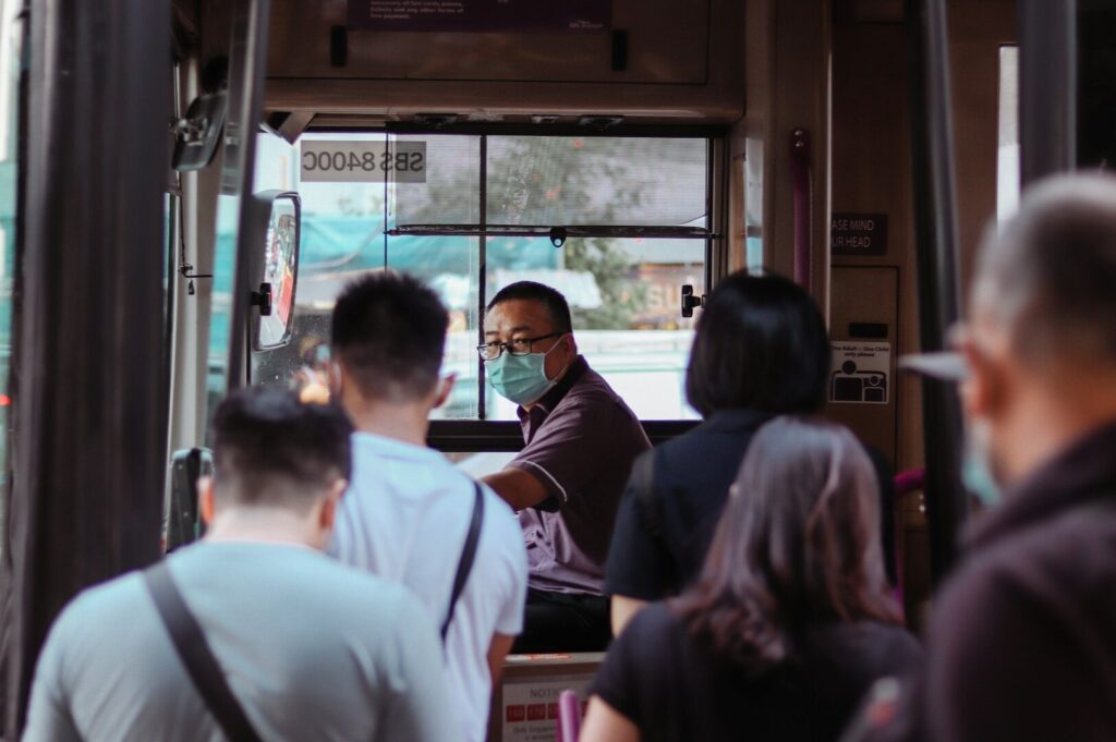 Passengers in face masks on a Singapore bus, showcasing safety measures in public transportation.