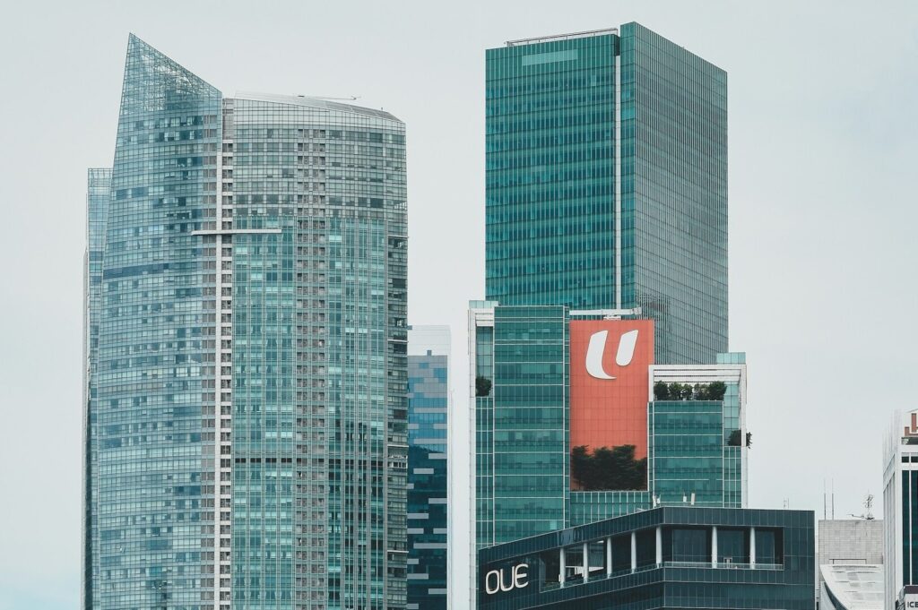 A skyline of tall buildings in Singapore's Financial District, featuring a prominent sign atop one of the structures.