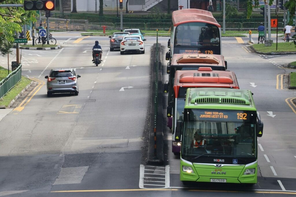A Singapore bus driving down a city street, showcasing urban transportation in action.