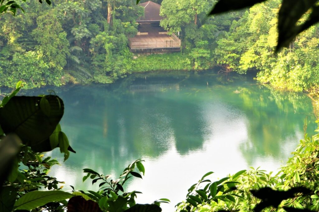 A wooden building near a serene and calm body of water at Bukit Timah Hill in Singapore.