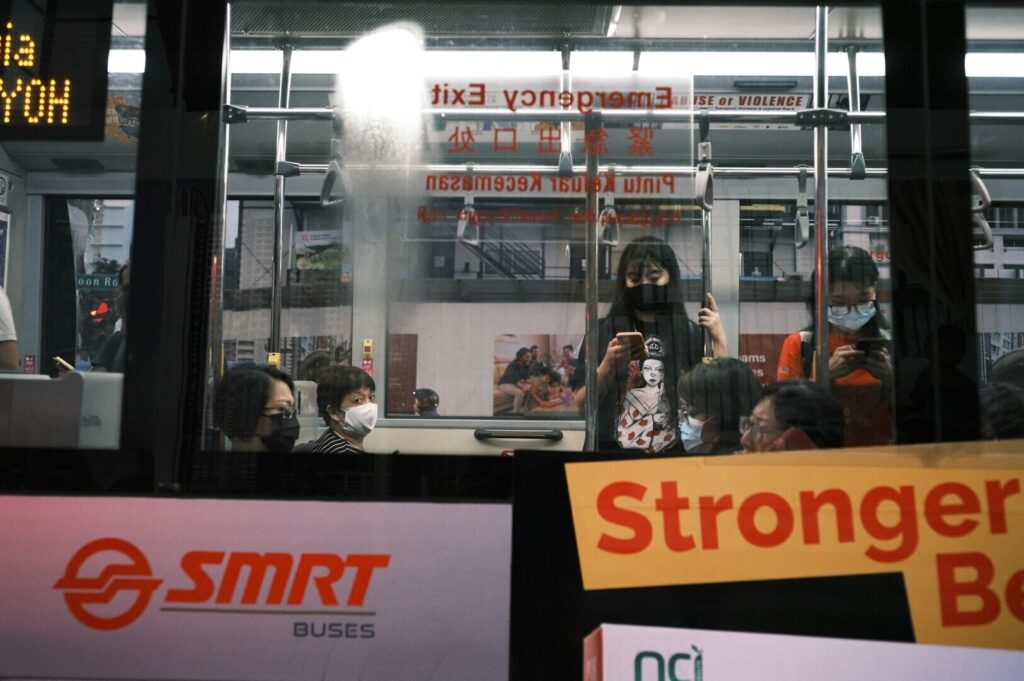 A Singapore bus filled with passengers, showcasing urban public transportation in a bustling city environment.