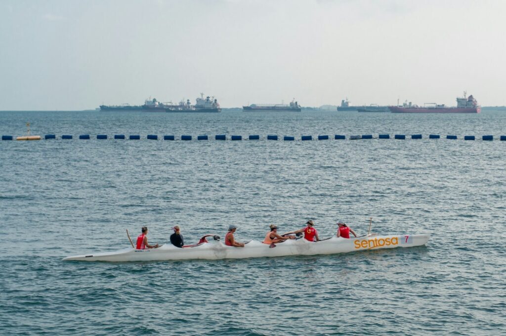 Participants in a dragon boat race in Singapore, working together in a colorful boat on the water.