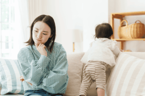 A thoughtful mom sits with her child in a cozy Singapore home, reflecting on the hiring process for domestic help. This candid moment highlights the emotional and practical considerations employers face when deciding to hire one helper or a new helper through a maid agency or employment agency. Topics like work permit application, helper's salary, levy concession, transfer maids, and subsequent FDW are part of the complete guide for expats hiring a foreign domestic worker or domestic helper. The image evokes themes of family, support, taking care of children, and the responsibilities involved in managing household services, costs, and obligations. It also touches on MOM regulations, manpower access, insurance, deductions, and the importance of choosing fair, eligible candidates while avoiding illegal practices.