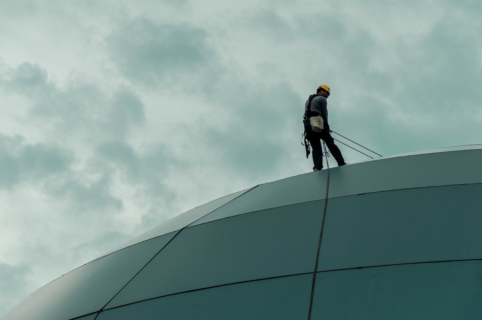 A Singaporean worker stands on a building rooftop, surveying the urban landscape below.