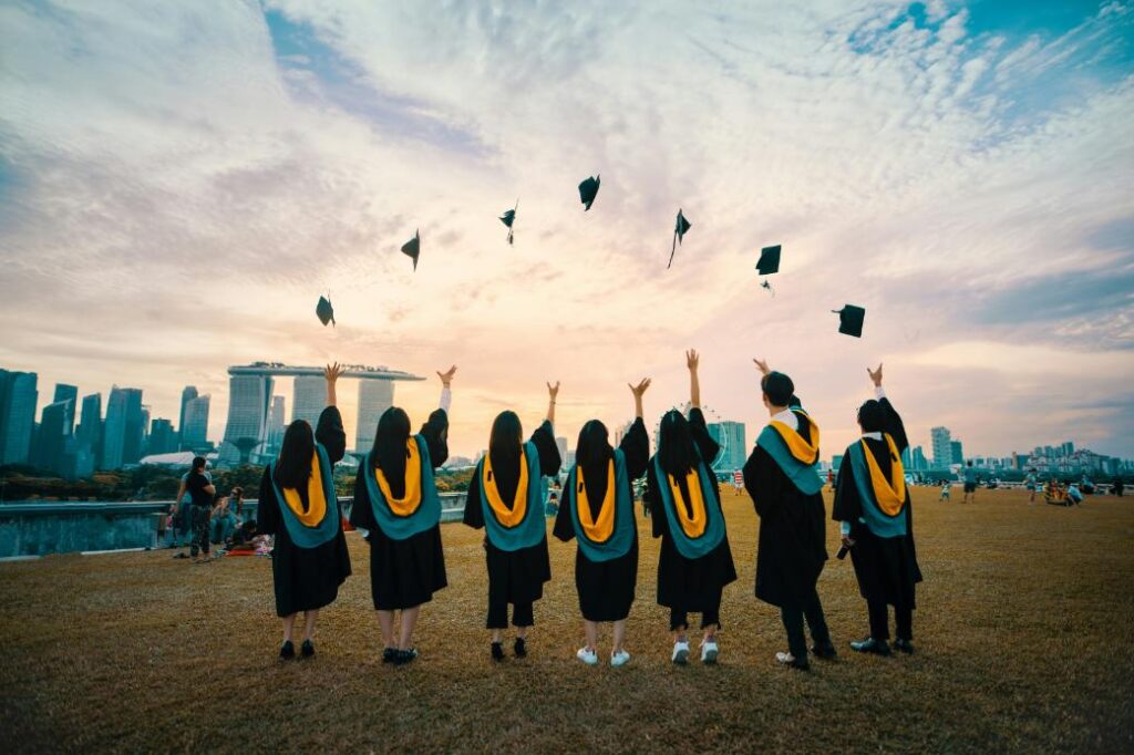 A photo of a group of students throwing their graduation caps with the Marina Bay Sands in the background.