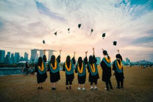 A photo of a group of students throwing their graduation caps with the Marina Bay Sands in the background.