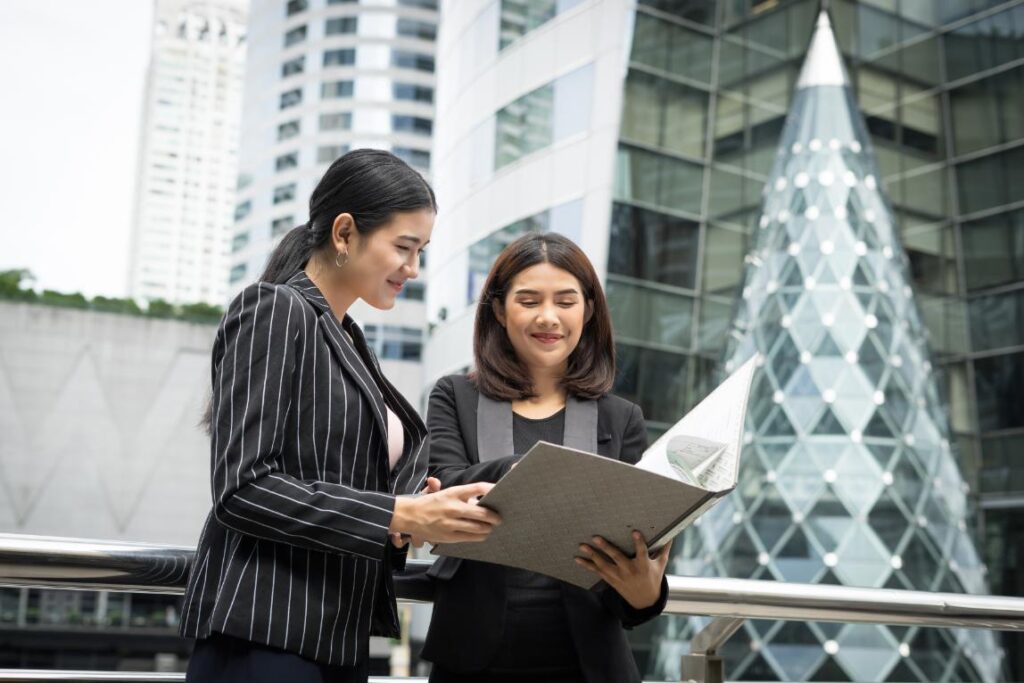 A photo of two employees proudly looking over their work as they stand outside of their building.