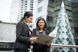 A photo of two employees proudly looking over their work as they stand outside of their building.
