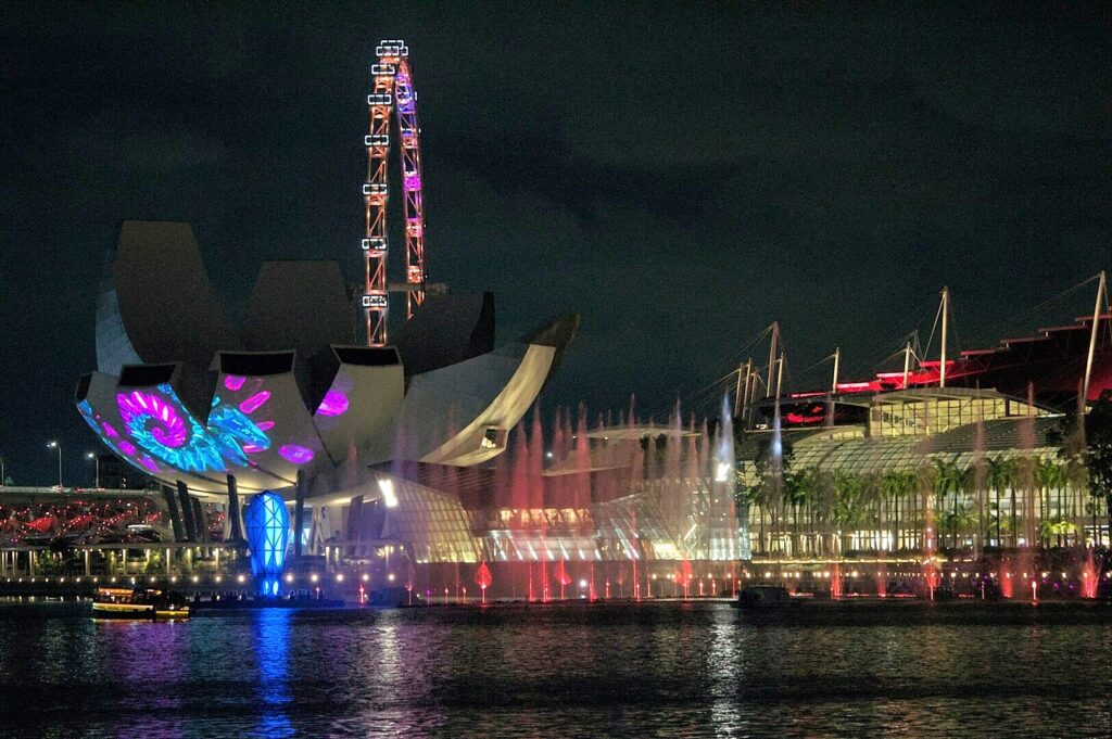 Marina Bay illuminated at night, featuring the ArtScience Museum in Singapore against a vibrant city skyline.