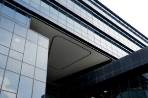 A modern university building in Singapore featuring a large glass wall and a prominent clock.
