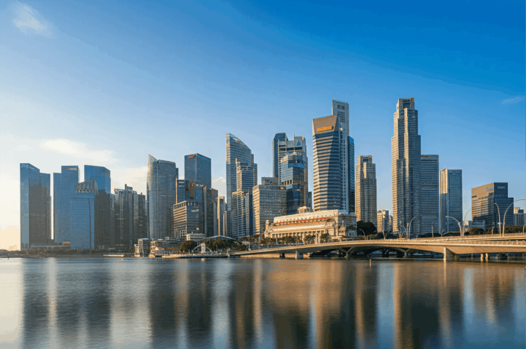 Modern waterfront skyline with glass skyscrapers and a bridge under a clear blue sky.