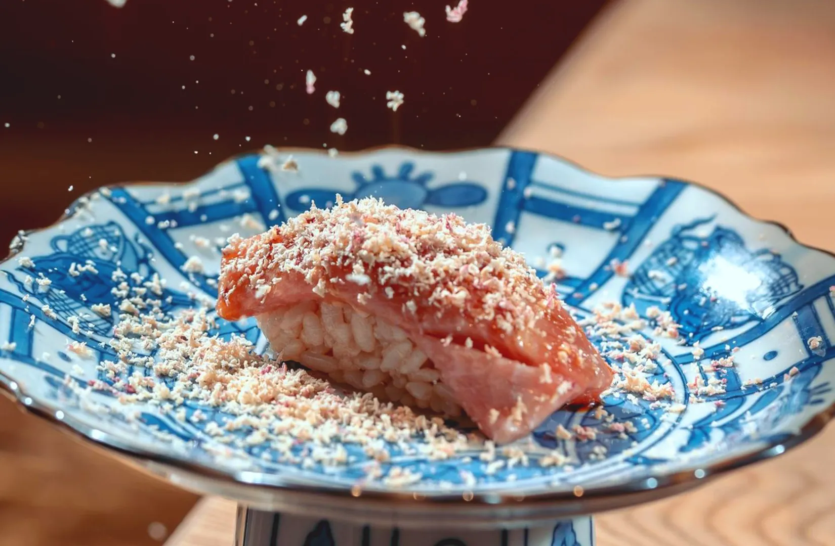 Salmon nigiri sushi topped with grated garnish on ceramic plate