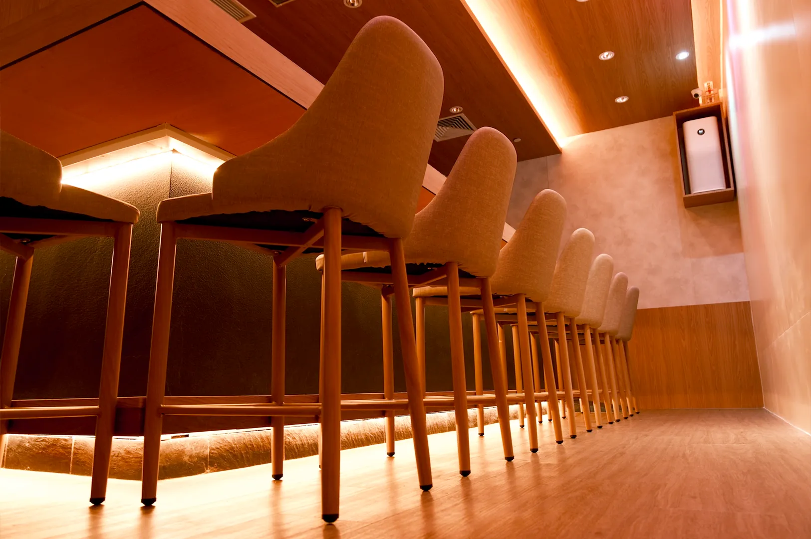 Minimalist sushi bar seating with warm lighting and wooden interior
