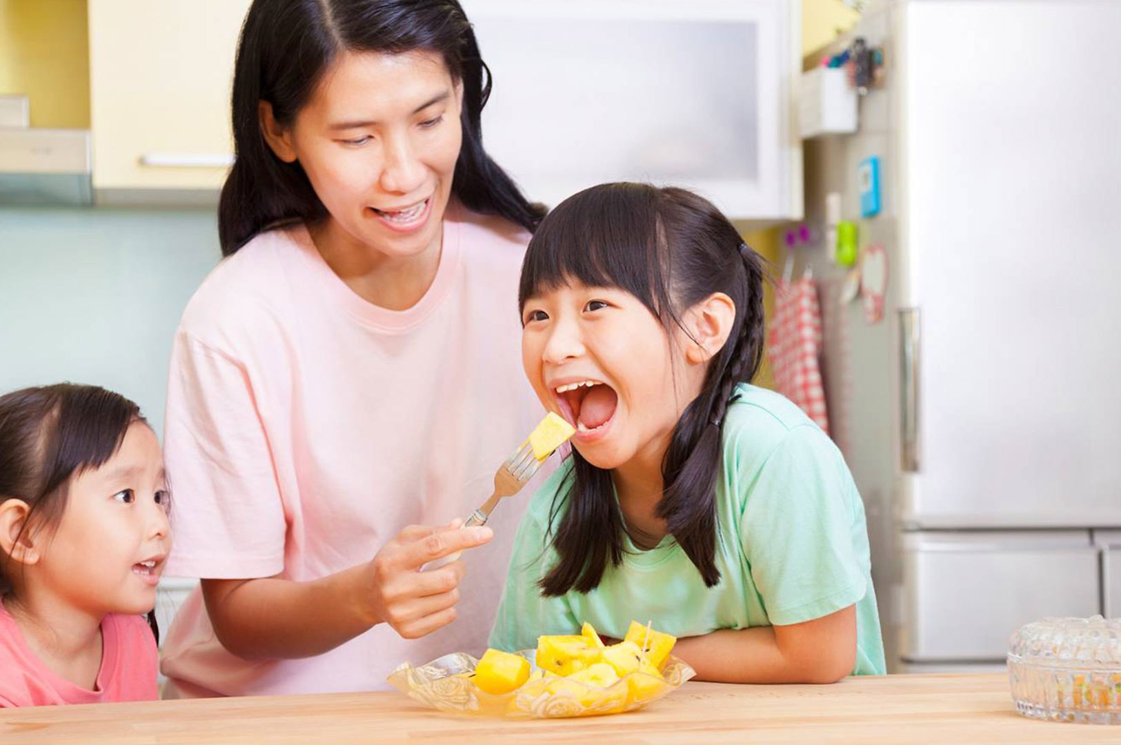 Domestic helper feeding fruit to children at home in Singapore.