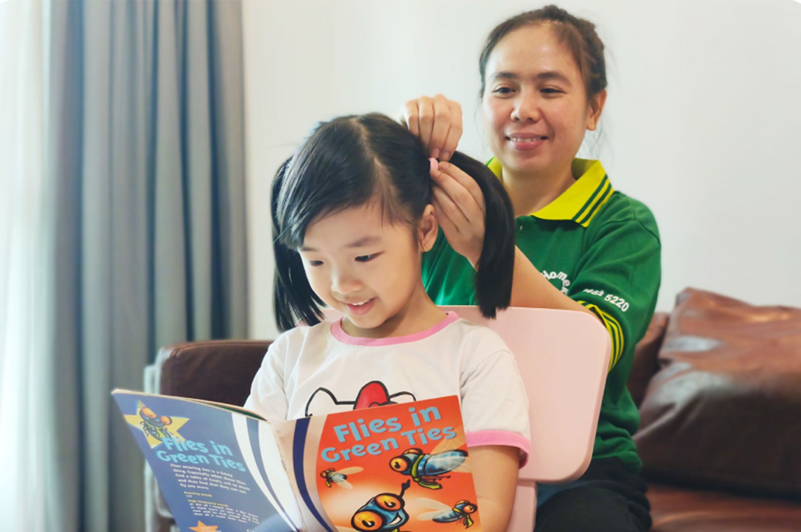 Domestic helper helping a child read at home in Singapore.
