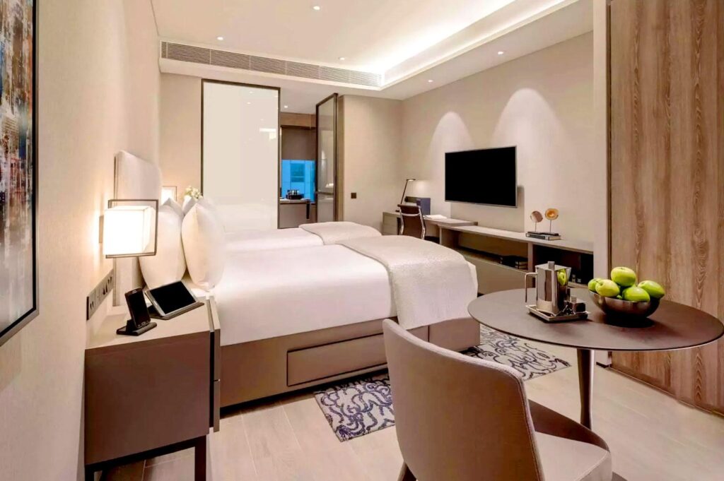 Modern serviced apartment room with bed, desk, and kitchenette.