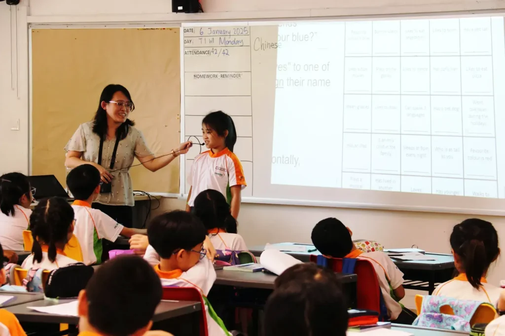 Singapore primary school classroom with teacher guiding students during lesson, showcasing MOE education and interactive learning environment