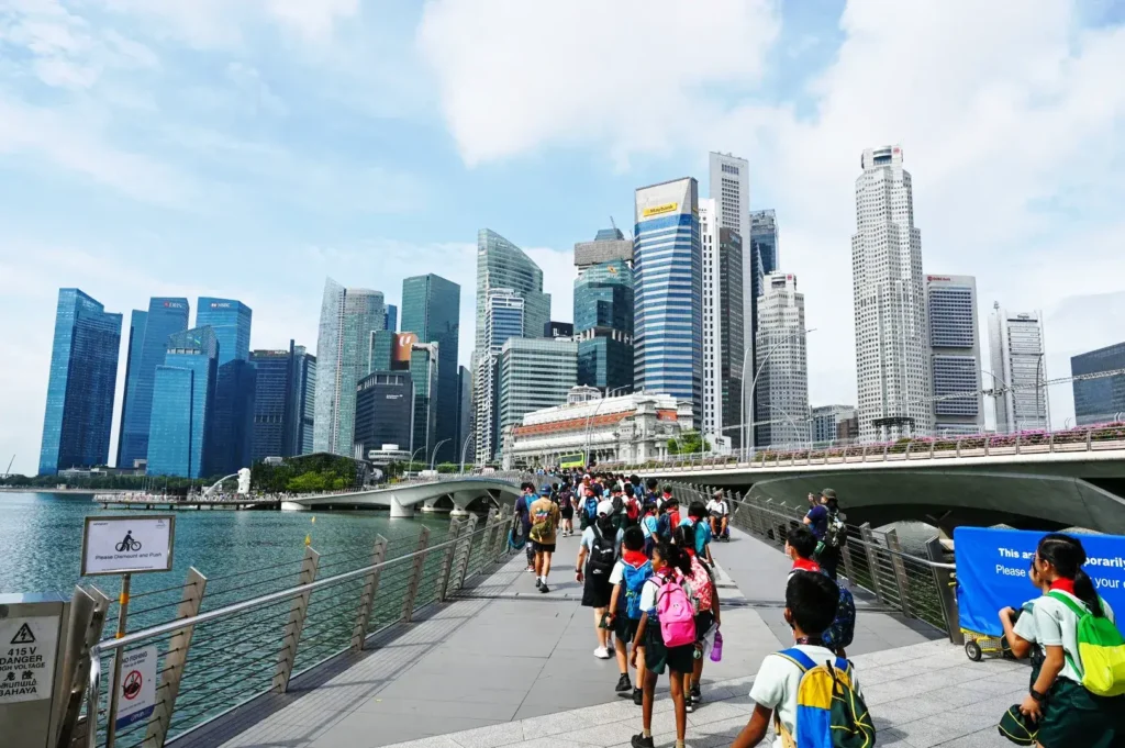 Singapore primary school students walking along Marina Bay waterfront with city skyline during school activity or field trip