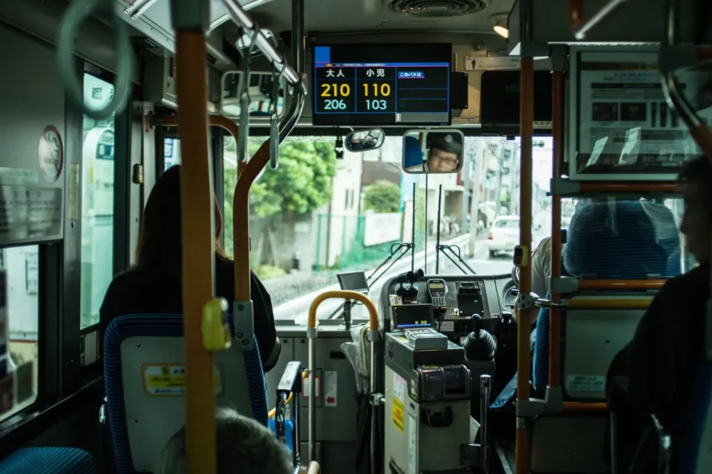 An interior view looking down the aisle of an empty public transit bus featuring bright yellow grab bars and rows of blue passenger seats.
