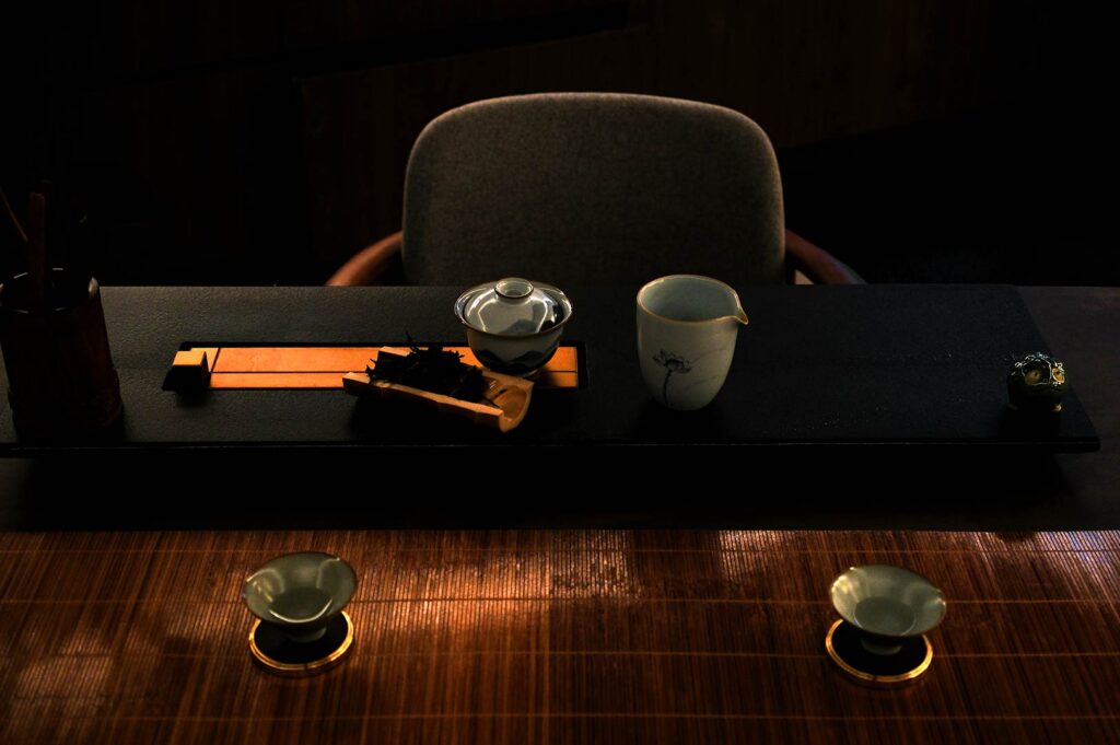 Premium gongfu tea setup in Singapore with porcelain gaiwan, tea leaves, and minimalist private tea tasting table