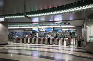 A modern subway station with multiple ticket gates and digital display boards showing information.