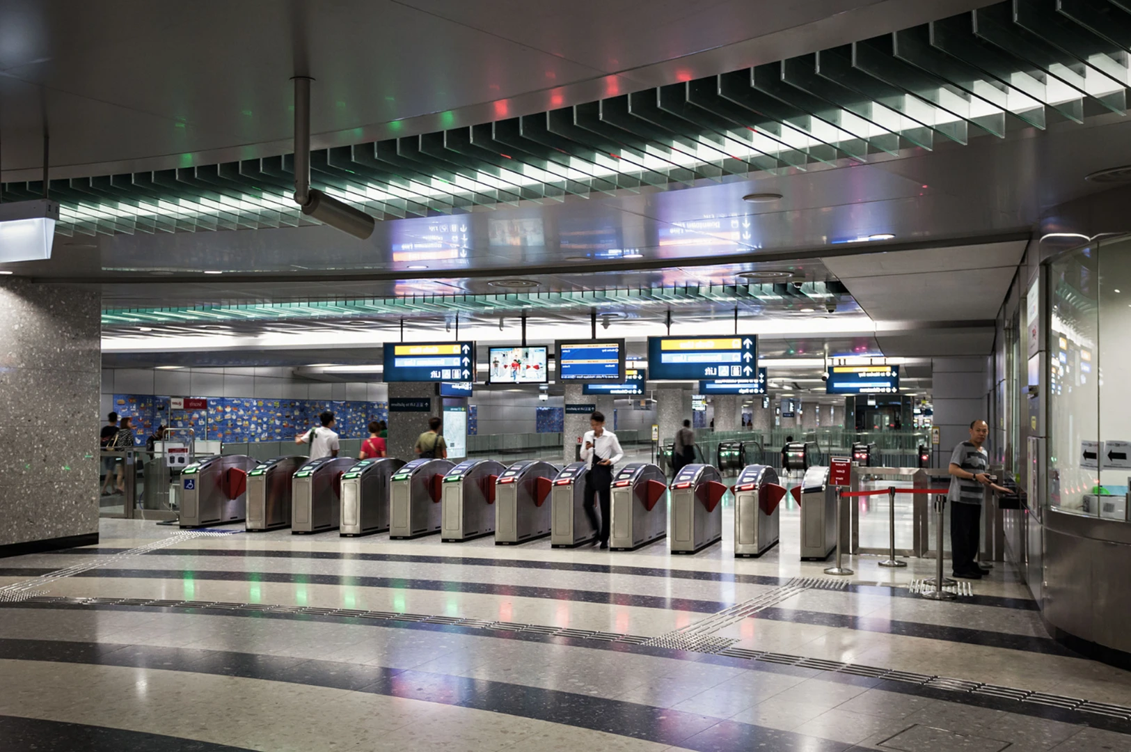 A modern subway station with multiple ticket gates and digital display boards showing information.
