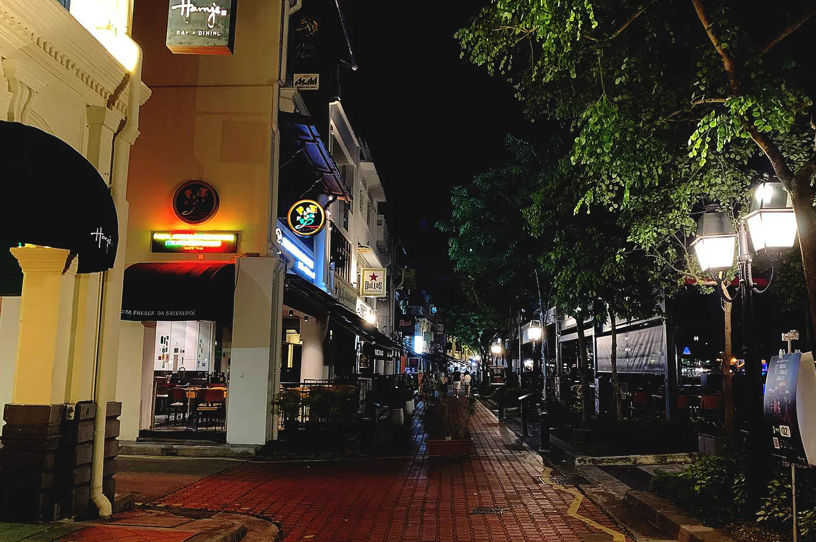 quiet Singapore street at night with warm lights and empty walkway reflecting peaceful evening walk without destination