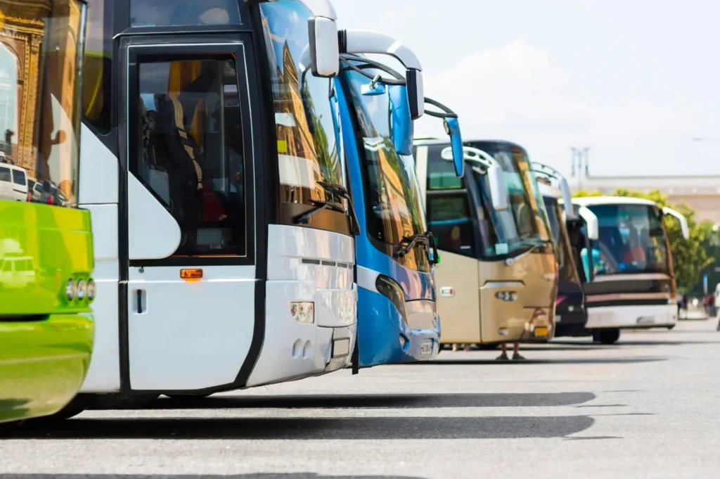 Public transit buses parked side by side in an open-air depot lot during a clear day.