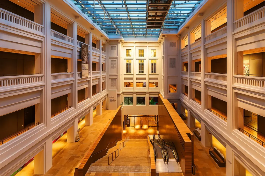 Elegant atrium hallway inside National Gallery Singapore featuring contemporary museum architecture and warm lighting