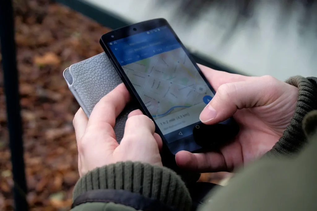 A close-up shot of a hand holding a smartphone displaying a route navigation screen on Google Maps.
