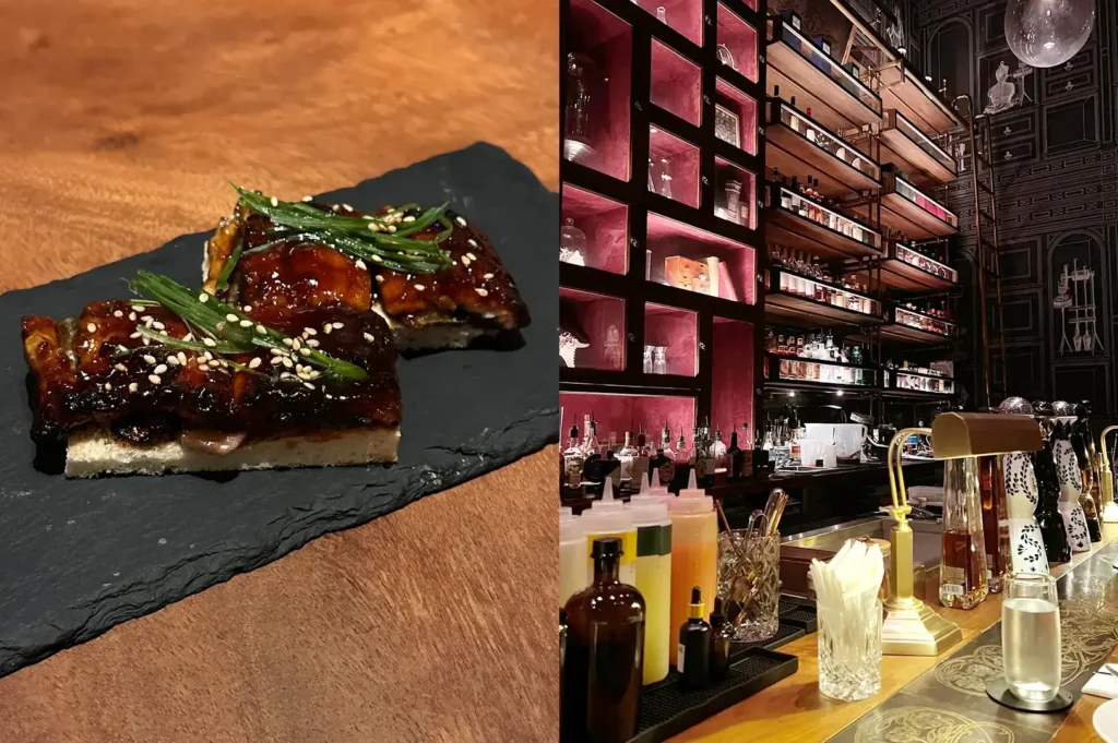 Glazed beef ribs on slate and restaurant bar with pink-lit shelving.