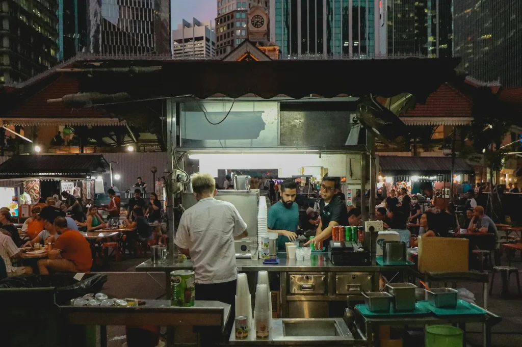 Bustling Singapore hawker center at night with food stalls and diners.