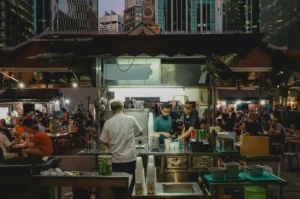 Bustling Singapore hawker center at night with food stalls and diners.