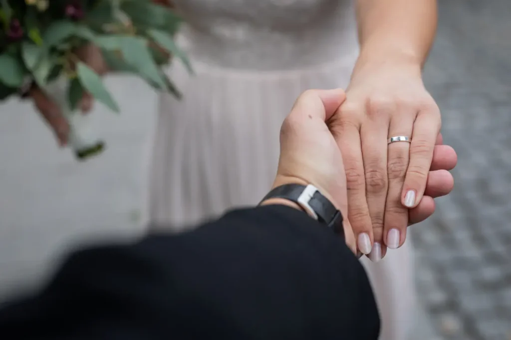 Bride and groom holding hands with rings.